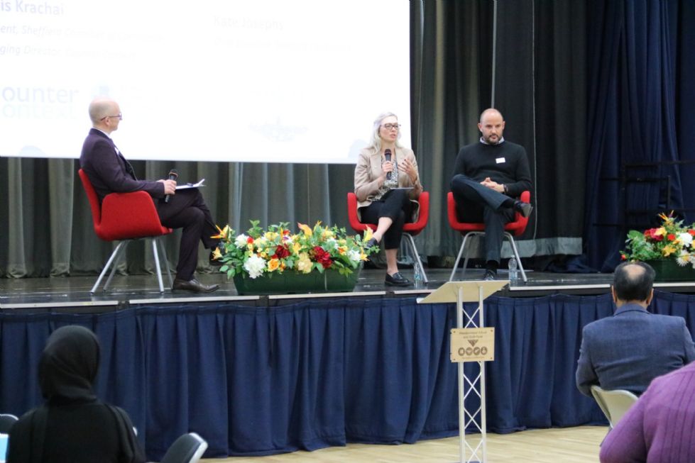 the chief executive of Sheffield City Council and the President of the Sheffield  Chamber of Commerce sit in chairs on the school stage and talk to the audience