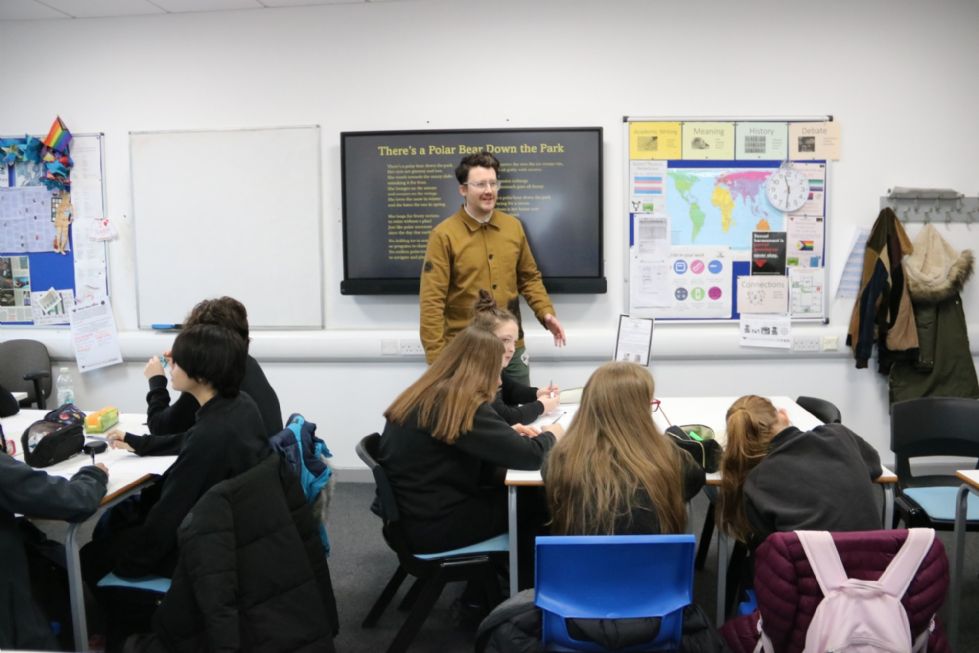  students writing poetry at a workshop led by a poet in school