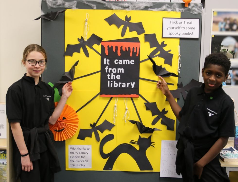 y7 students stand next to their halloween display in the library