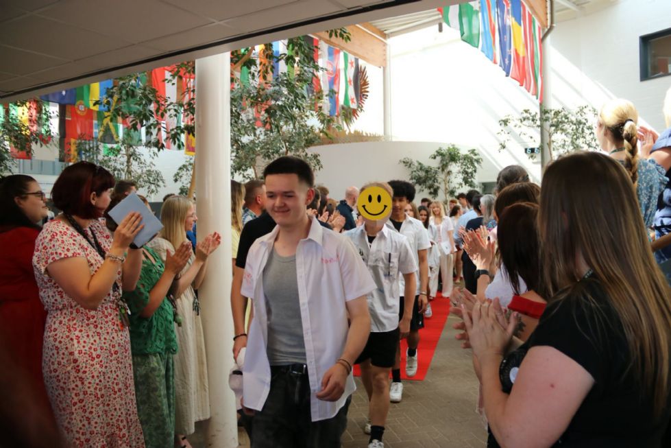 students walking on the red carpet, staff clapping