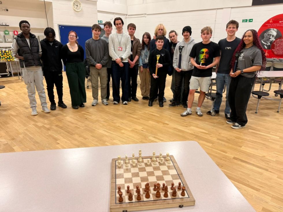 students stand behind a chess board after the tournament