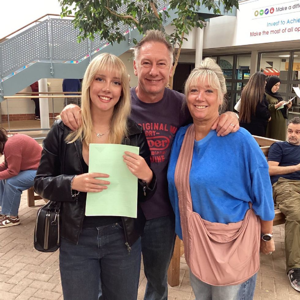 student smiling with their parents after receiving their GCSE results
