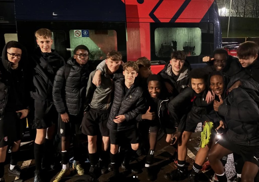 y10 footballers pose for photograph next to the school minibus