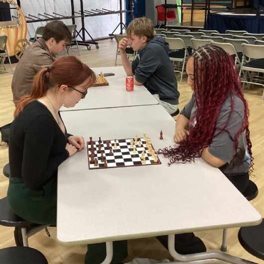 students sitting at a table across from one another playing chess