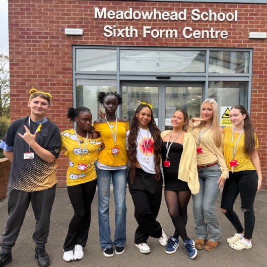 sixth form students stand outside the sixth form centre wearing yellow for mental health awareness